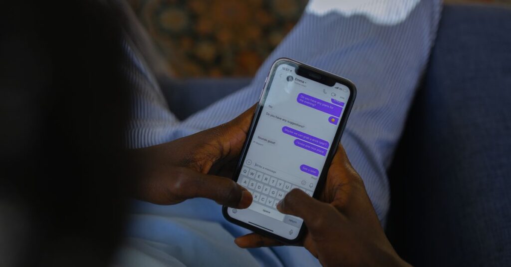 Close-up of hands holding a smartphone, typing a message on a touch screen indoors.